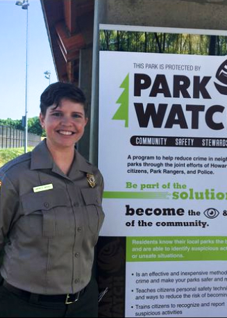 Amy Carpenter Driscoll stand in front of a sign for Park Watch a program she started