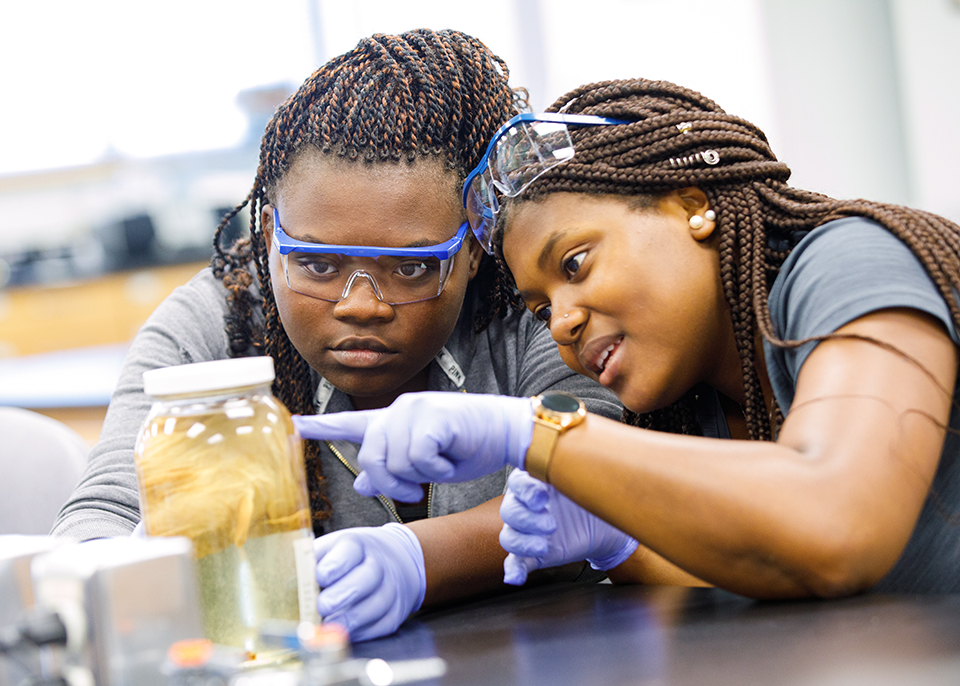 2 female students observe jar in lab class