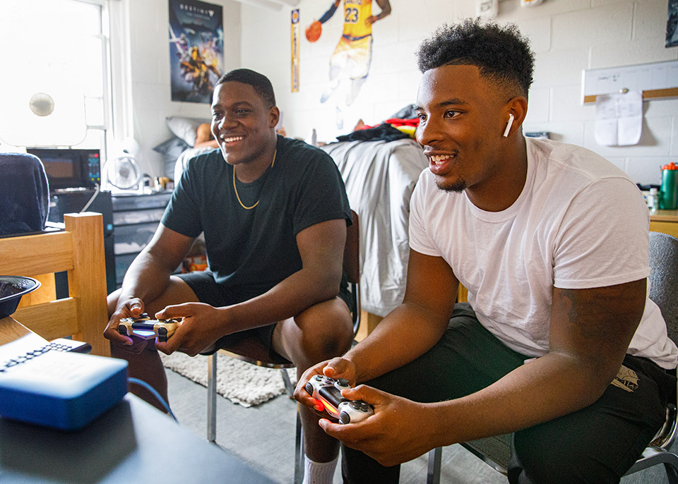 males students playing video game in dorm room