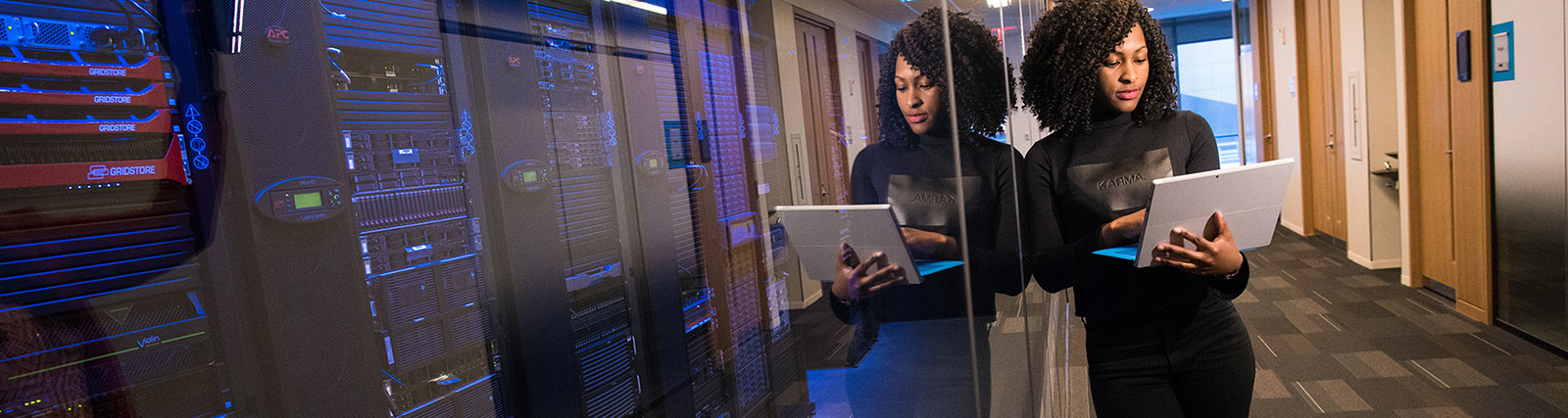 female computer specialist standing near servers