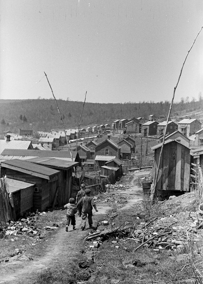 children walking down a path through shacks