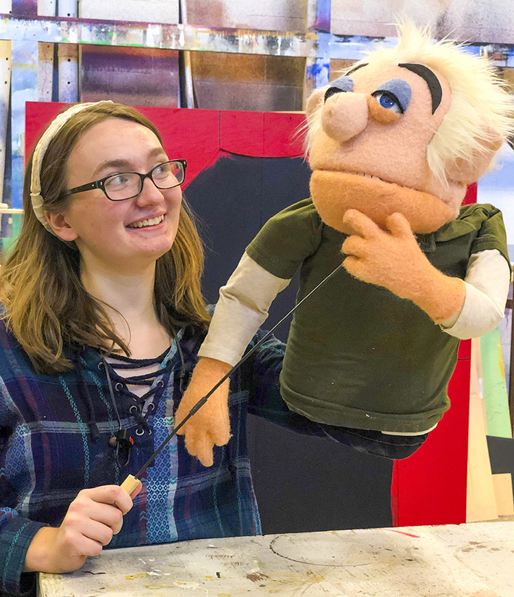 female sutdent holds up her puppet