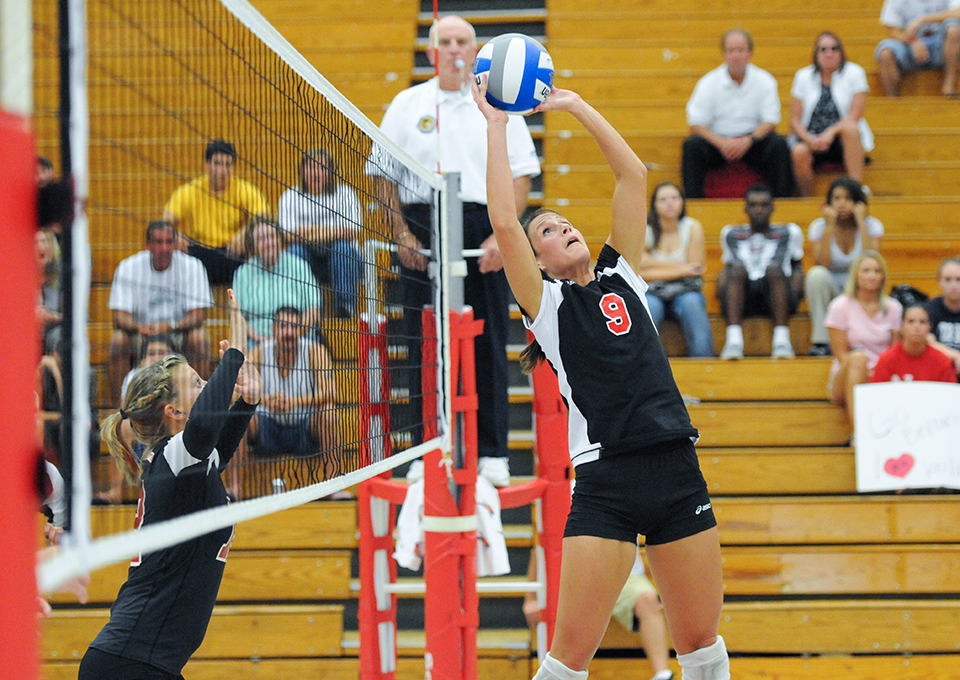 femal vollyeball player sets ball at net