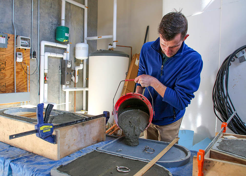 kodi bowers pours mixed concrete into a pre-made form