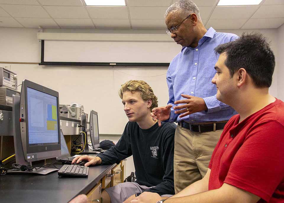 Professor and two students discussing results viewed on the computer screen