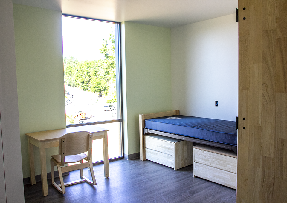photo of bed and desk near floor to ceiling window