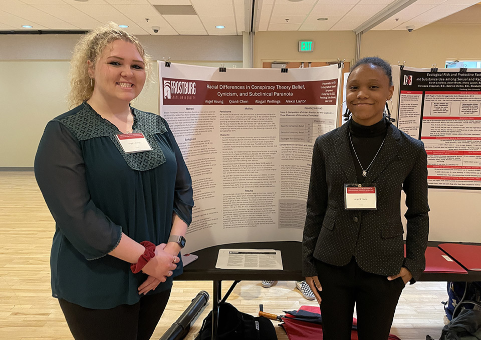 students pose with poster at undergraduate research symposium