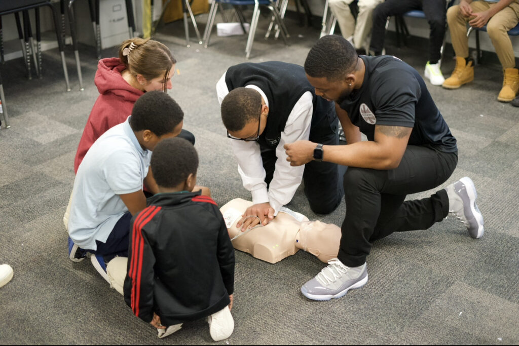 A group of four students with instructor in CPR activity