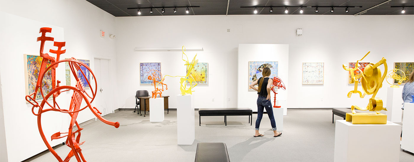 A student takes in various works of art in the Roper Art Gallery