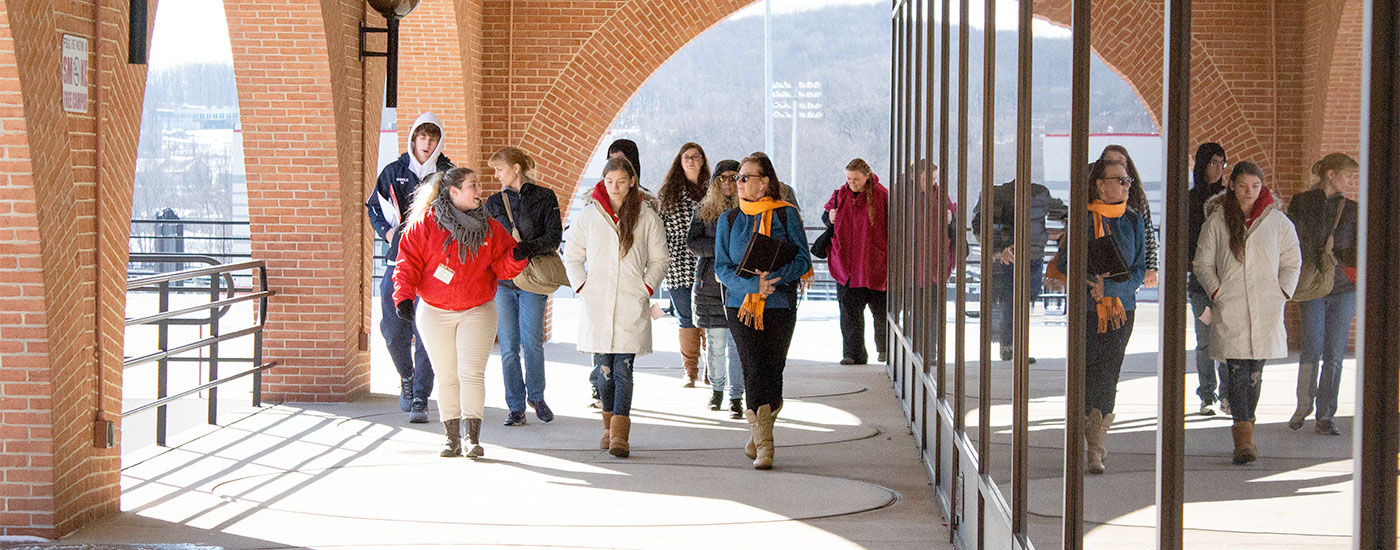 A Frostburg State Student Admissions Ambassador chats with parents and students while walking and giving a tour of campus