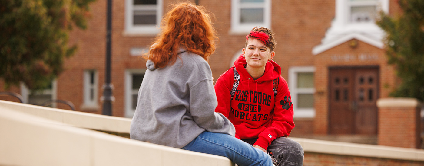 Students talking sitting on a wall at a quad