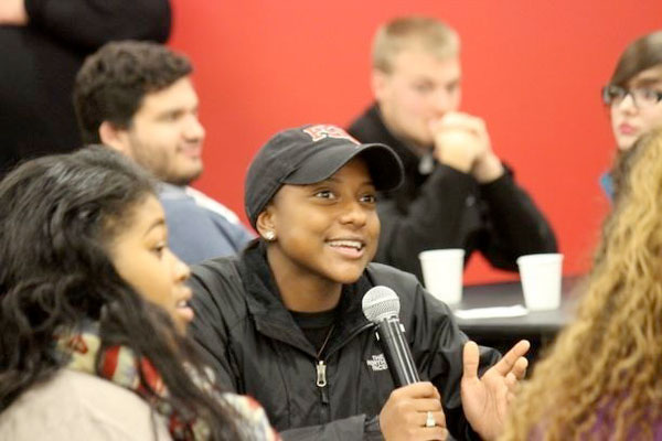 A female student talks into a microphone during a group discussion