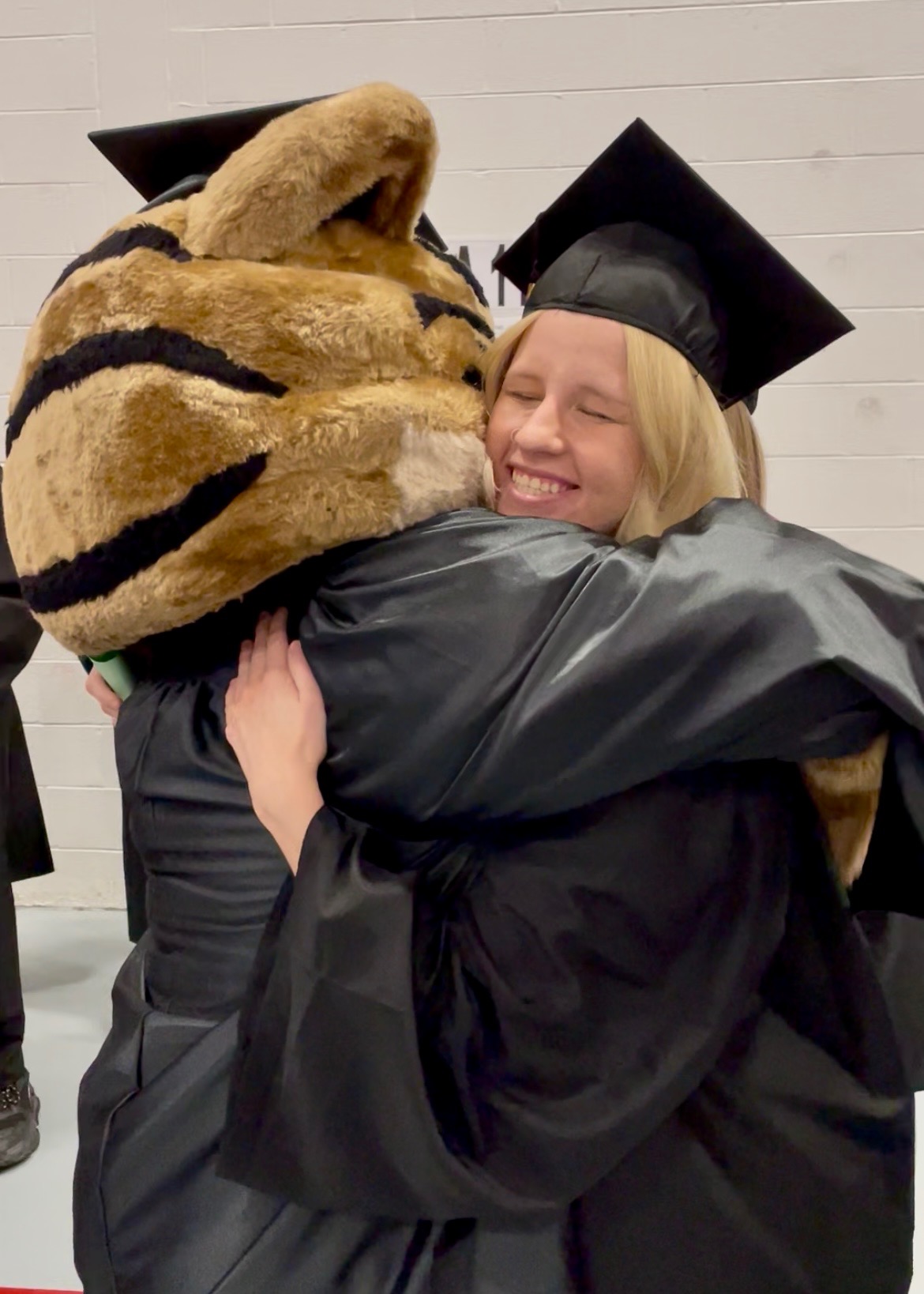 Bob E. Cat mascot hugging graduate