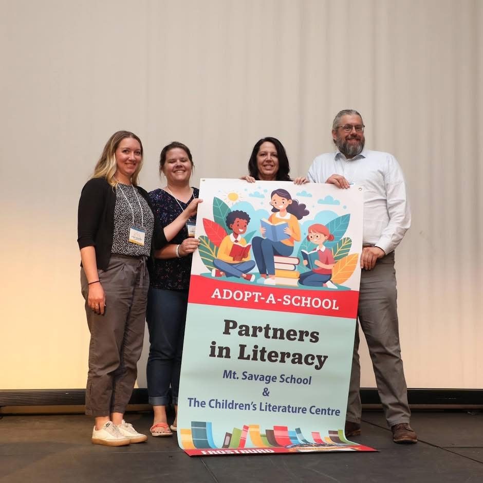 4 People holding a banner that highlights Mt. Savage Elementary as the 2026-2028 Adopt-A-School