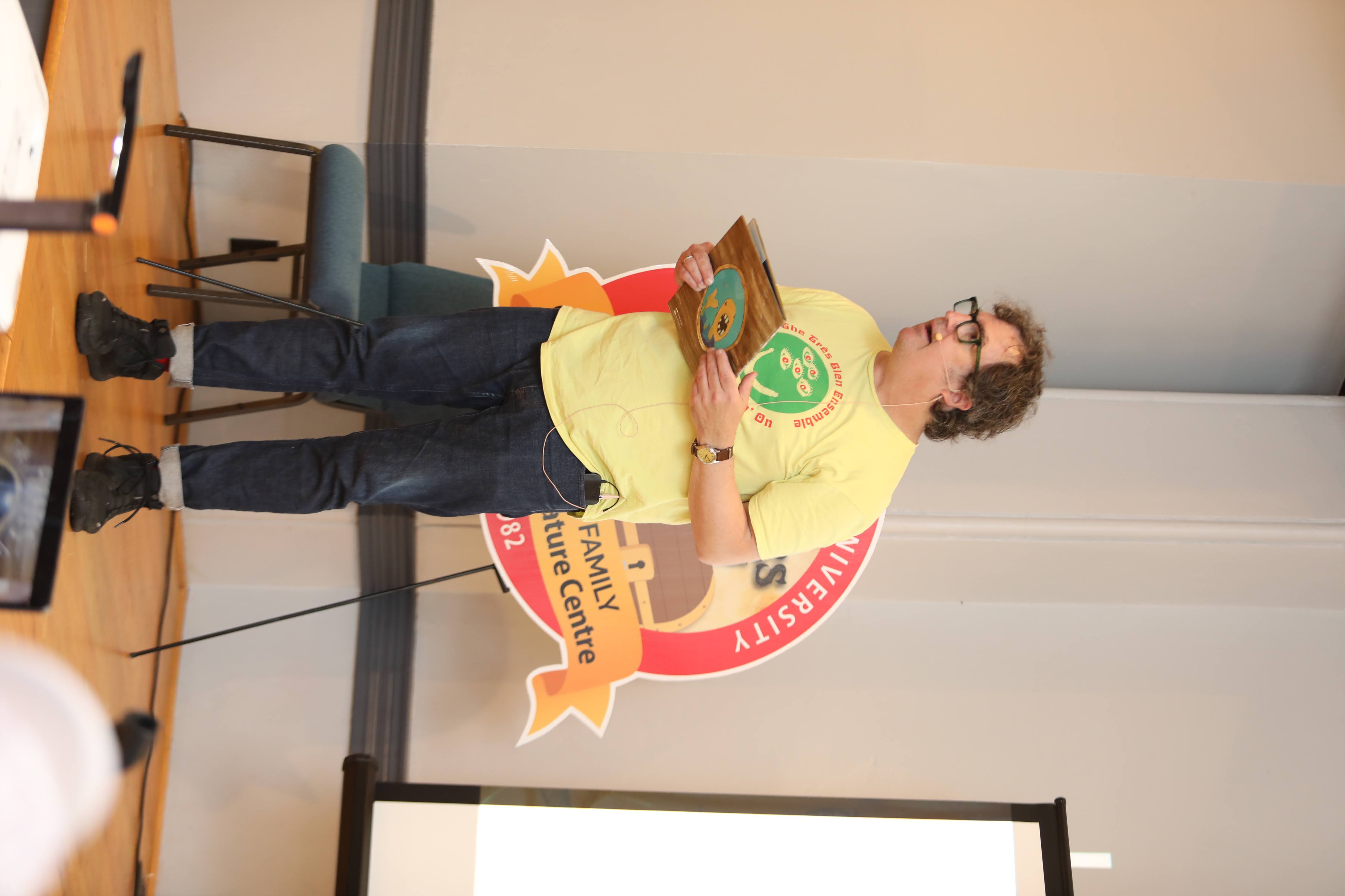 Matt James standing on a stage presenting to children