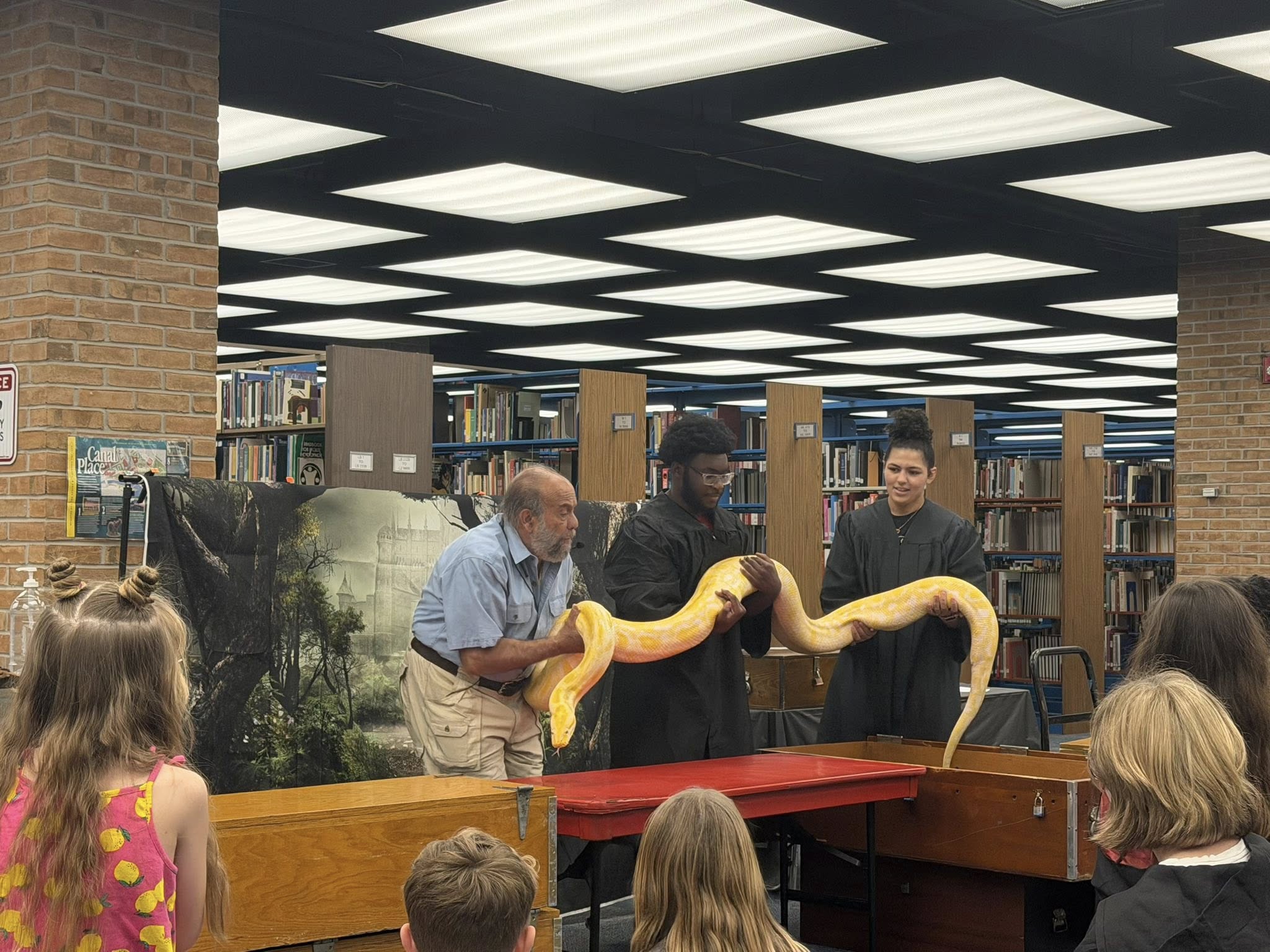 Snake handler and wizards holding large yellow snake