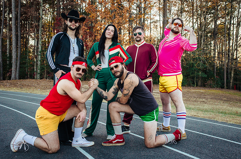 Holy Roller band members in 80's style track and fitness attire pose on track in late Fall.