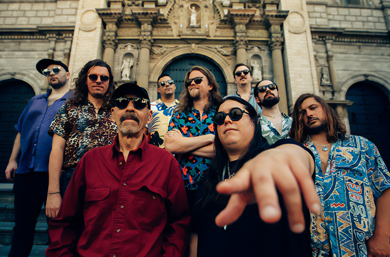 ¡Tumbao! Band members standing outside of stone monument on front steps