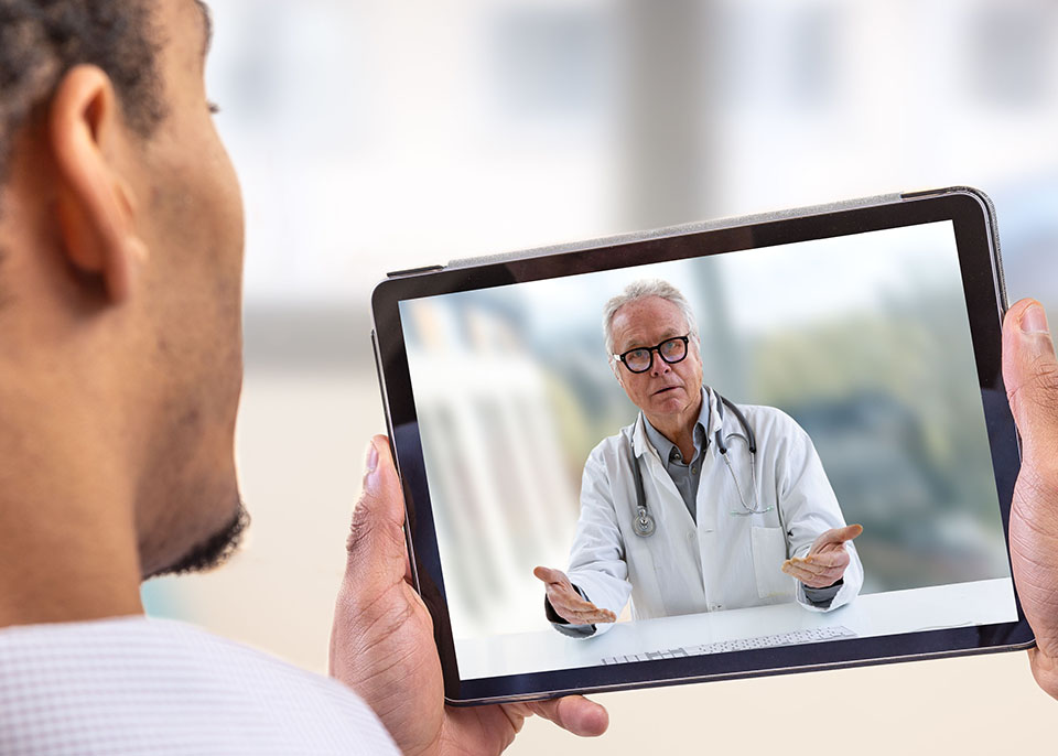 man viewing tablet video conferencing with doctor