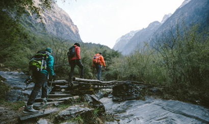 Group of hikers go across wet boulders