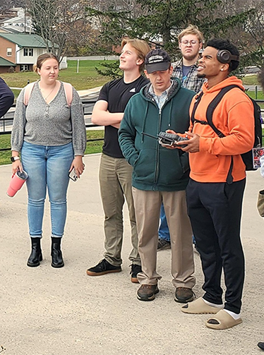 students watch another student fly a drone