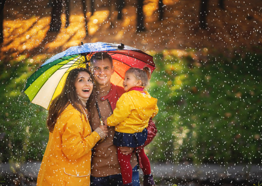 family standing beneath umbrella in rain