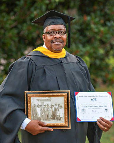 Charles Able in commencement atire holding degree certificates