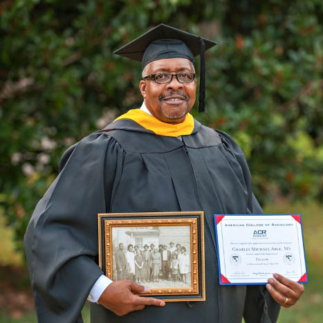 Charles Able in commencment regalia hold degrees