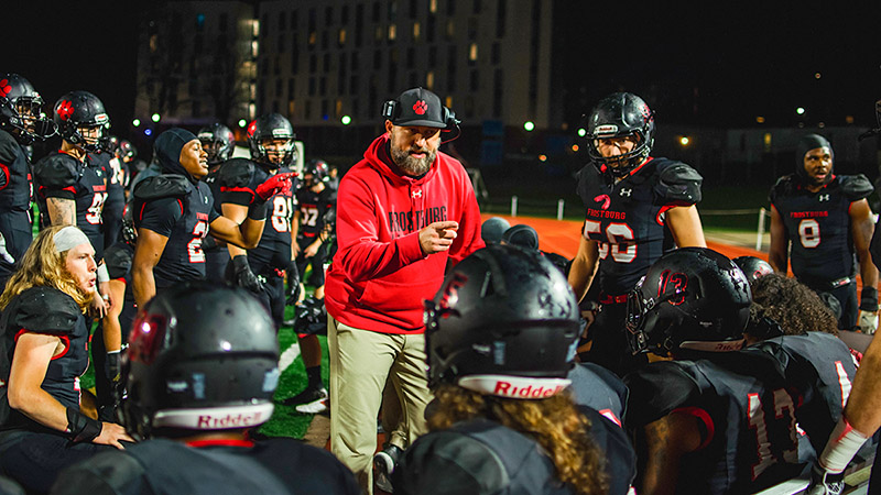 Coach Wagoner talks to team on sidelines at night game