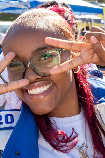 Student smiling showing two peace signs with both hands