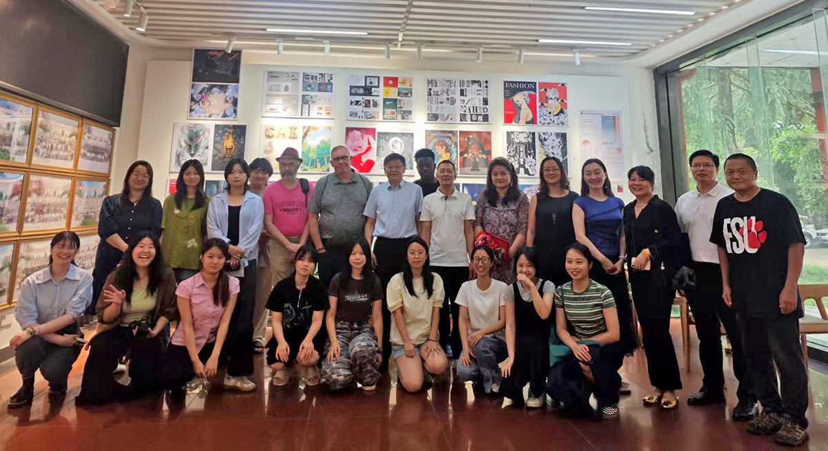 Group of students and faculty posing together inside an art gallery with colorful artwork displayed on the walls behind them